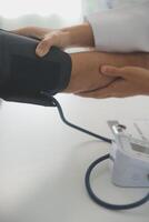 Male doctor uses a blood pressure monitor to check the body pressure and pulse of the patients who come to the hospital for check-ups, Medical treatment and health care concept. photo