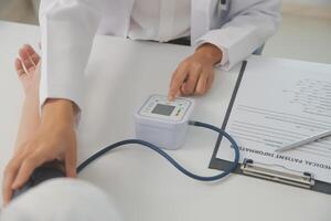 Male doctor uses a blood pressure monitor to check the body pressure and pulse of the patients who come to the hospital for check-ups, Medical treatment and health care concept. photo