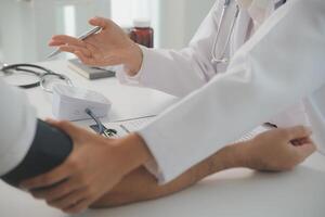 Male doctor uses a blood pressure monitor to check the body pressure and pulse of the patients who come to the hospital for check-ups, Medical treatment and health care concept. photo