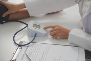 Male doctor uses a blood pressure monitor to check the body pressure and pulse of the patients who come to the hospital for check-ups, Medical treatment and health care concept. photo