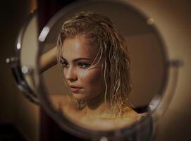 Sexy blonde girl with wet hair after bath loks in the mirror photo