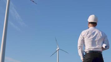 The engineer stands with his back to the camera on the background of windmills and rejoices with his hands raised video