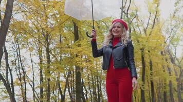 leende Lycklig kvinna höjer ett paraply med löv och de falla ner video