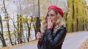 lindo jovem mulher tosse em pé de a guarda-chuva em uma frio outono dia. sazonal doenças, tosse, frio video