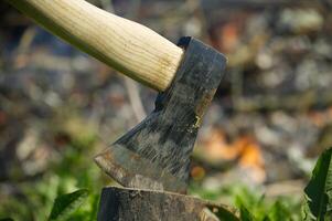 Close up of axe with a black blade stuck in a log photo