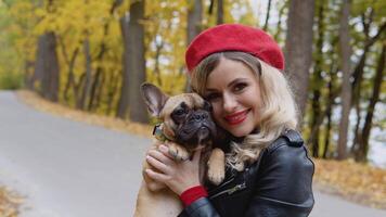 retrato de un sonriente contento alegre mujer con gracioso francés buldog en otoño parque video