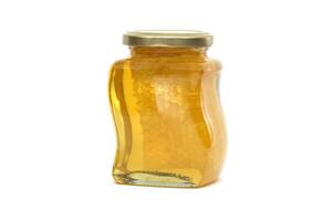 Glass jar filled with honey and honeycomb isolated on white photo