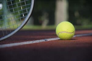 Tennis racquet and yellow tennis ball near white line photo