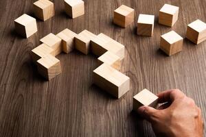 Hand forming bigger question mark. question mark on wooden table background photo