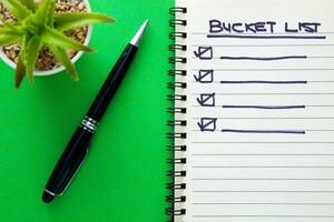 Bucket list on notebook with a pen. photo