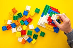 hand stacking up the colorful plastic block on yellow background photo