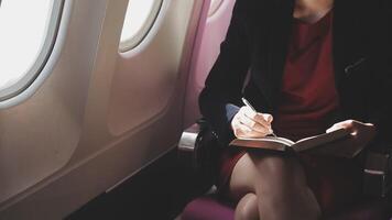 mujer joven asiática que usa una computadora portátil sentada cerca de las ventanas en primera clase en un avión durante el vuelo, los viajes y el concepto de negocios video