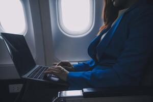 utilizando móvil y computadora portátil, pensativo asiático personas hembra persona a bordo, avión ventana, perfectamente capturar el anticipación y emoción de fiesta viajar. chino, japonés gente. foto