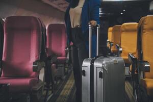 Asian female traveler putting luggage into overhead locker on airplane during boarding. photo