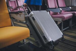 Asian female traveler putting luggage into overhead locker on airplane during boarding. photo