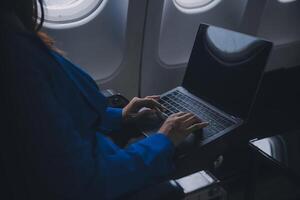 utilizando móvil y computadora portátil, pensativo asiático personas hembra persona a bordo, avión ventana, perfectamente capturar el anticipación y emoción de fiesta viajar. chino, japonés gente. foto