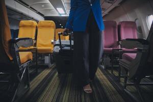 Asian female traveler putting luggage into overhead locker on airplane during boarding. photo