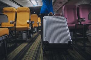 Asian female traveler putting luggage into overhead locker on airplane during boarding. photo