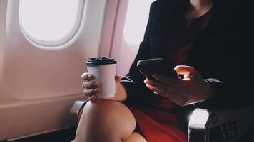 mujer joven asiática que usa una computadora portátil sentada cerca de las ventanas en primera clase en un avión durante el vuelo, los viajes y el concepto de negocios video