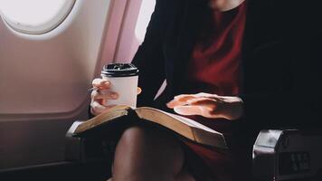 mujer joven asiática que usa una computadora portátil sentada cerca de las ventanas en primera clase en un avión durante el vuelo, los viajes y el concepto de negocios video