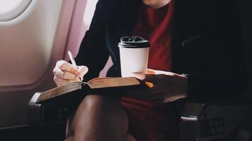 mujer joven asiática que usa una computadora portátil sentada cerca de las ventanas en primera clase en un avión durante el vuelo, los viajes y el concepto de negocios video