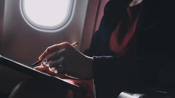 asiatische junge frau, die einen laptop verwendet, der während des fluges, der reise und des geschäftskonzepts in der ersten klasse im flugzeug in der nähe von fenstern sitzt video