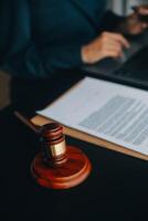 Justice and law concept.Male judge in a courtroom with the gavel, working with, computer and docking keyboard, eyeglasses, on table in morning light photo