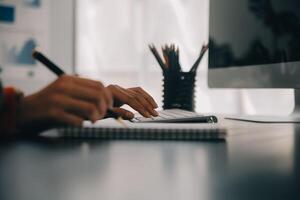 Asian Business woman using calculator and laptop for doing math finance on an office desk, tax, report, accounting, statistics, and analytical research concept photo