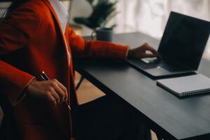 Asian Business woman using calculator and laptop for doing math finance on an office desk, tax, report, accounting, statistics, and analytical research concept photo