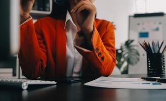 Asian Business woman using calculator and laptop for doing math finance on an office desk, tax, report, accounting, statistics, and analytical research concept photo