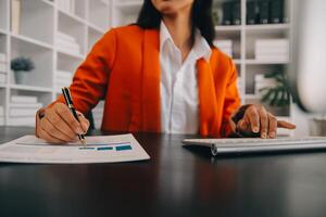 Asian Business woman using calculator and laptop for doing math finance on an office desk, tax, report, accounting, statistics, and analytical research concept photo