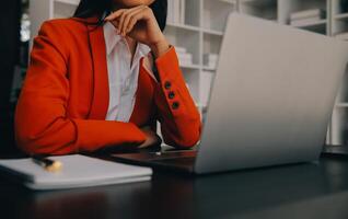 Asian Business woman using calculator and laptop for doing math finance on an office desk, tax, report, accounting, statistics, and analytical research concept photo