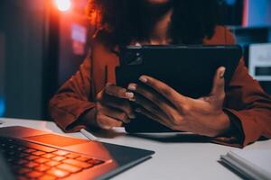 mujer sentado a su escritorio en hogar oficina trabajando tarde a noche utilizando ordenador portátil computadora web diseñador trabajando tiempo extraordinario remotamente desde hogar foto