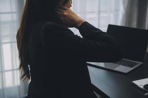 Asian Businesswoman Using laptop computer and working at office with calculator document on desk, doing planning analyzing the financial report, business plan investment, finance analysis concept. photo