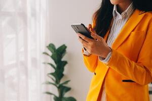 Young smiling business woman using smartphone near computer in office, copy space photo