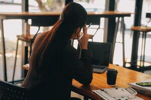 Asian women are stressed while working on laptop, Tired asian businesswoman with headache at office, feeling sick at work, copy space photo