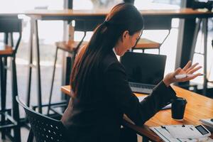 las mujeres asiáticas están estresadas mientras trabajan en una laptop, una mujer de negocios asiática cansada con dolor de cabeza en la oficina, se siente enferma en el trabajo, copia espacio foto