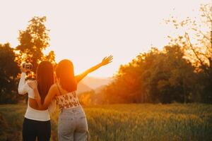 Young pretty woman in red summer dress and straw hat walking on yellow farm field with ripe golden wheat enjoying warm evening. photo