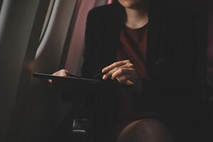 rubia hembra turista comprobación entrante notificación en teléfono inteligente sentado en asiento de avión con netbook.joven mujer de negocios compartir medios de comunicación desde teléfono en ordenador portátil computadora durante avión vuelo foto