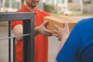 Asian delivery express courier young man use giving boxes to woman customer he wearing protective face mask at front home photo