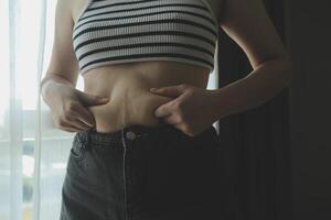 Women body fat belly. Obese woman hand holding excessive belly fat. diet lifestyle concept to reduce belly and shape up healthy stomach muscle. photo