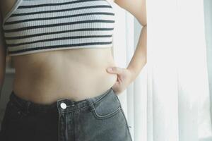 mujer cuerpo grasa barriga. obeso mujer mano participación excesivo barriga gordo. dieta estilo de vida concepto a reducir barriga y forma arriba sano estómago músculo. foto