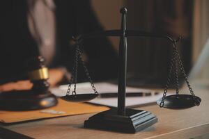 Business and lawyers discussing contract papers with brass scale on desk in office. Law, legal services, advice, justice and law concept picture with film grain effect photo