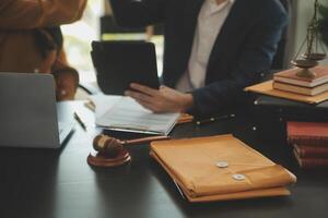 Justice and Law concept. Legal counsel presents to the client a signed contract with gavel and legal law or legal having team meeting at law firm in background photo