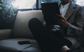 Happy businessman dressed in suit in modern office using tablet photo