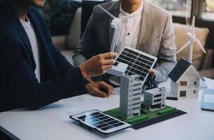 dos joven ingenieros pericia en solar célula instalación reuniones y discusión en el trabajo. planificación a Instalar en pc solar fotovoltaica paneles en techo parte superior en el oficina habitación con fábrica edificio plan. foto