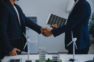 dos joven ingenieros pericia en solar célula instalación reuniones y discusión en el trabajo. planificación a Instalar en pc solar fotovoltaica paneles en techo parte superior en el oficina habitación con fábrica edificio plan. foto