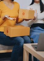 Asian SME business women use laptop computer checking customer order online shipping boxes at home. Starting Small business entrepreneur SME freelance. Online business, Work at home concept. photo