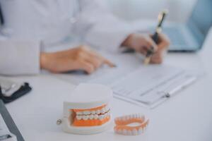 los dentistas están discutiendo problemas dentales al informar la imagen de rayos X en la pantalla del portátil a los pacientes. foto