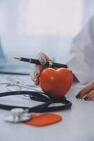 Doctor explaining heart to elderly patient. Doctor explaining the heart model. Doctors pen point to a model of the heart photo